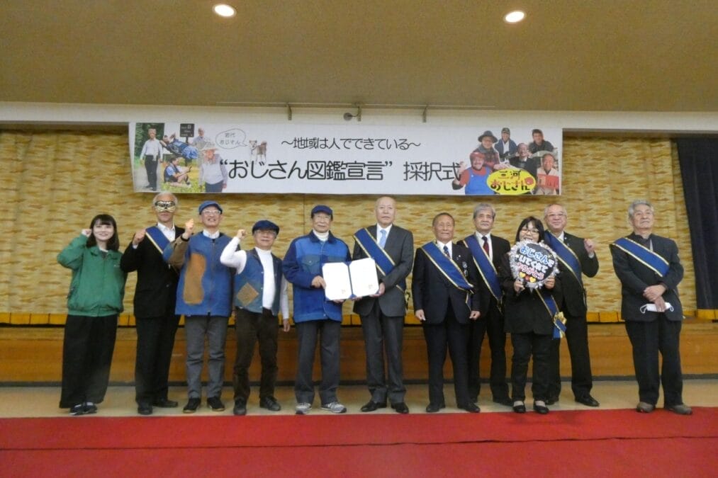 ステージに人が立っている(二本松市岩代地域おじさん図鑑宣言の式典)